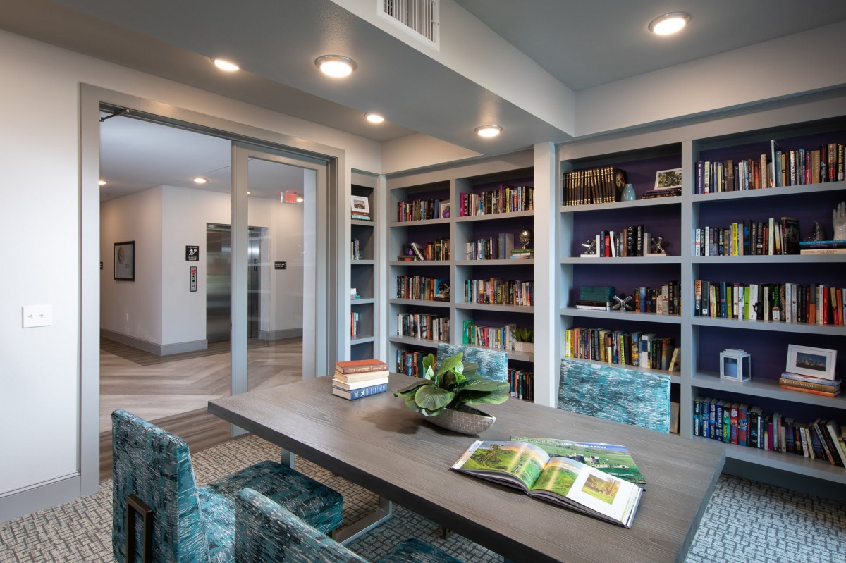 A modern library with teal chairs and bookshelves filled with books.