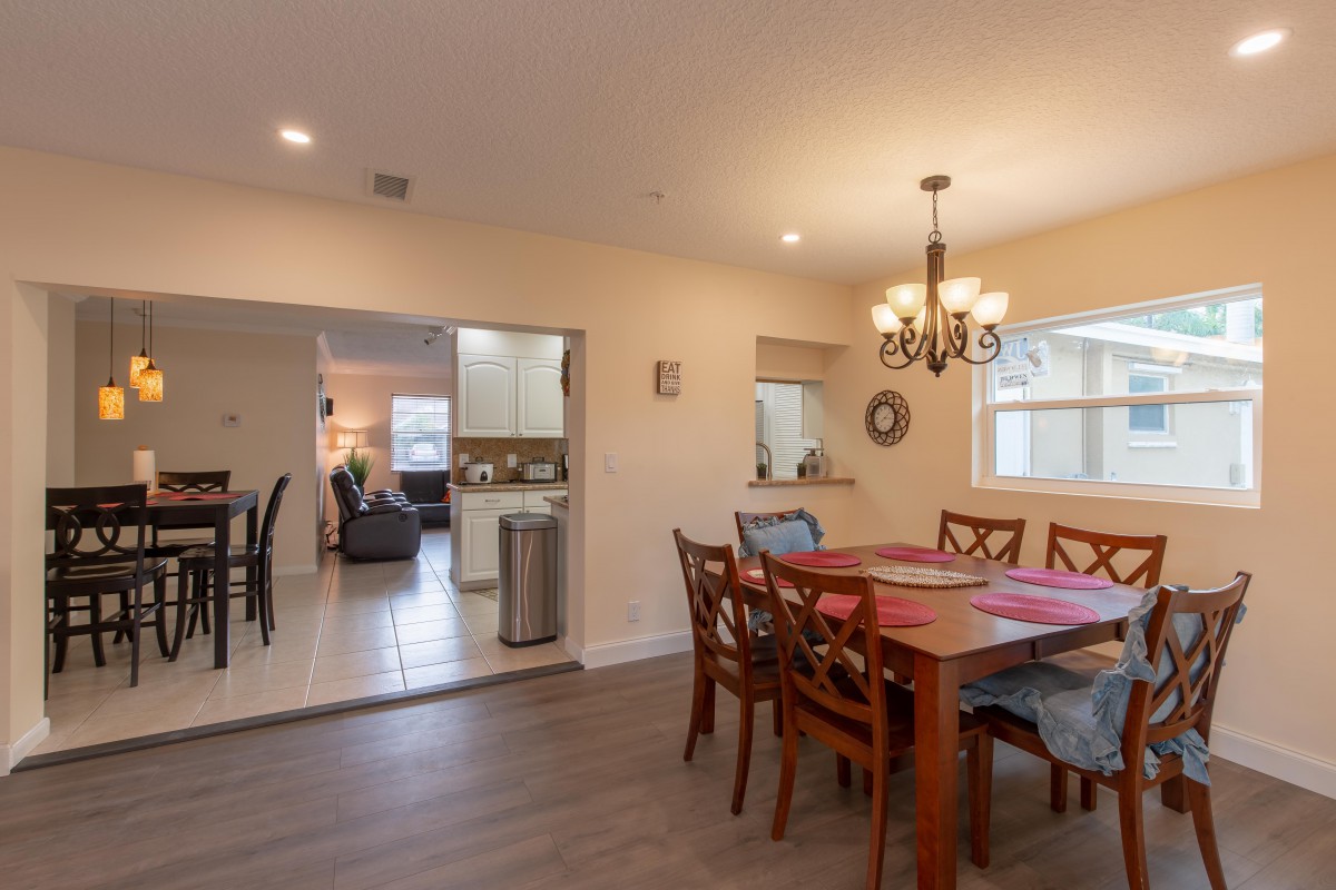 A cozy dining room with wooden furniture, adjacent to a kitchen and living area.