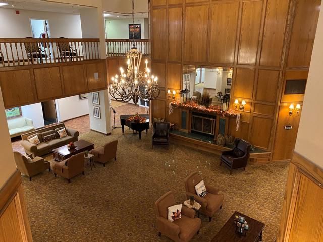 A cozy lobby with elegant wood paneling, a grand chandelier, and comfortable seating around a fireplace.