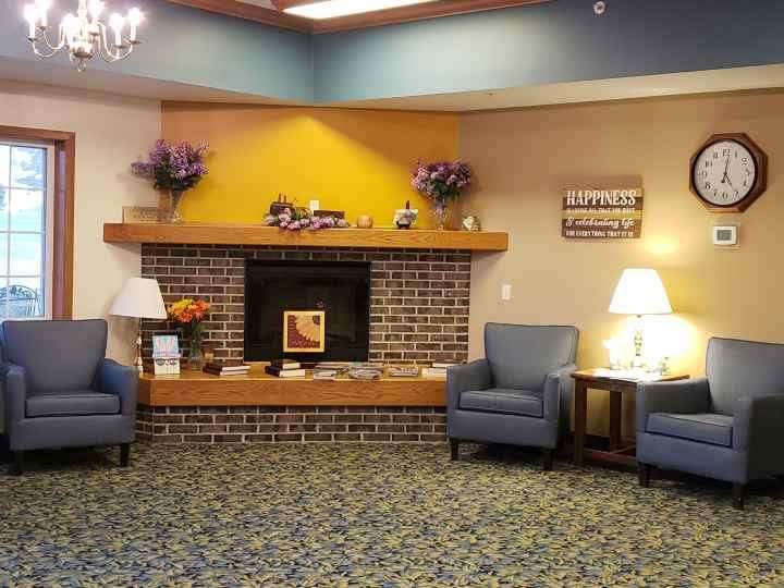 A cozy lobby area featuring a brick fireplace, comfortable chairs, and soft lighting.