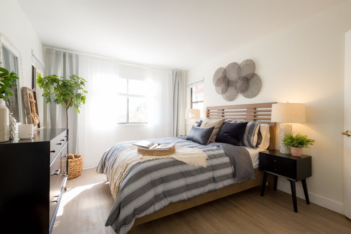 A modern and cozy bedroom with striped bedding and ample natural light.