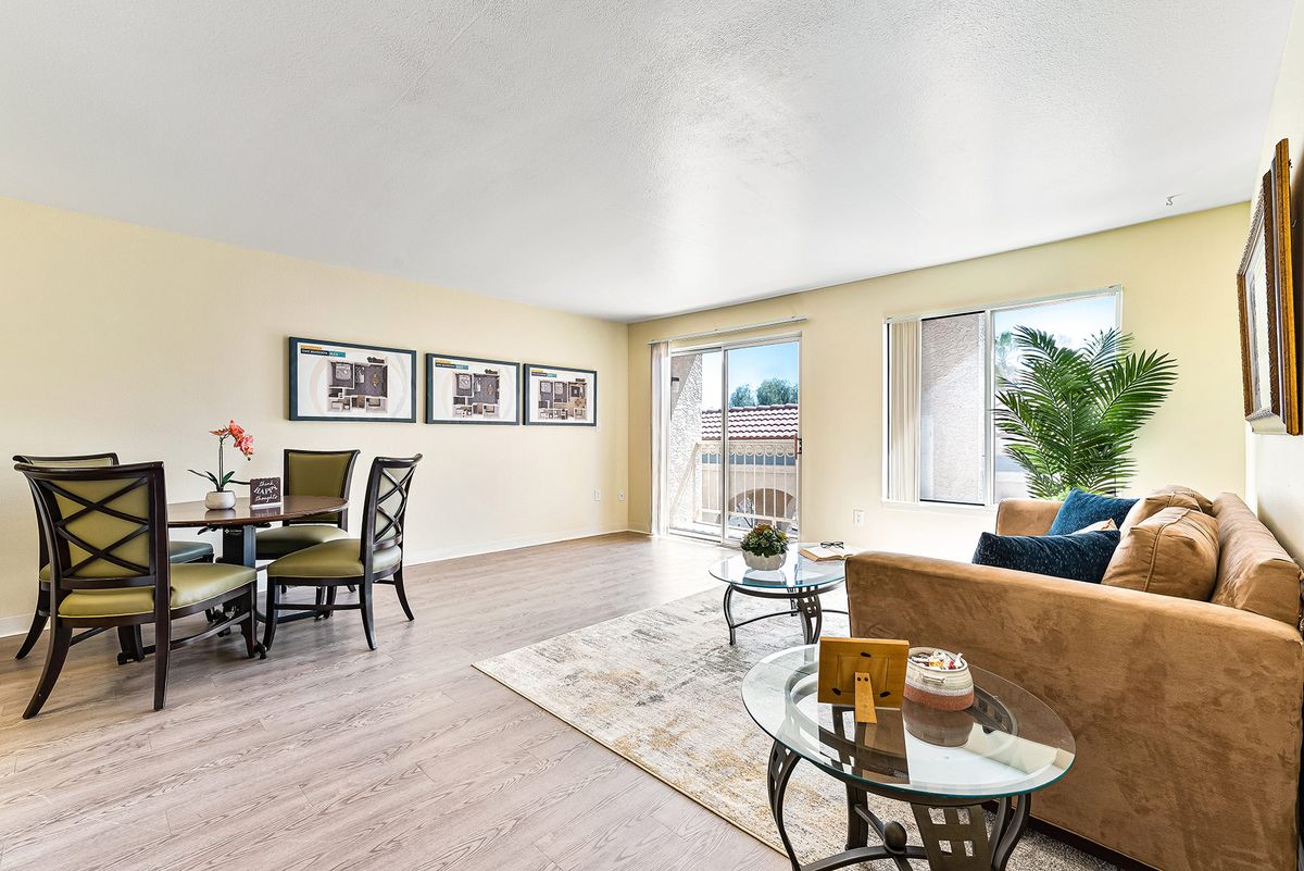 A spacious living and dining area with modern furnishings, wood flooring, and ample natural light.