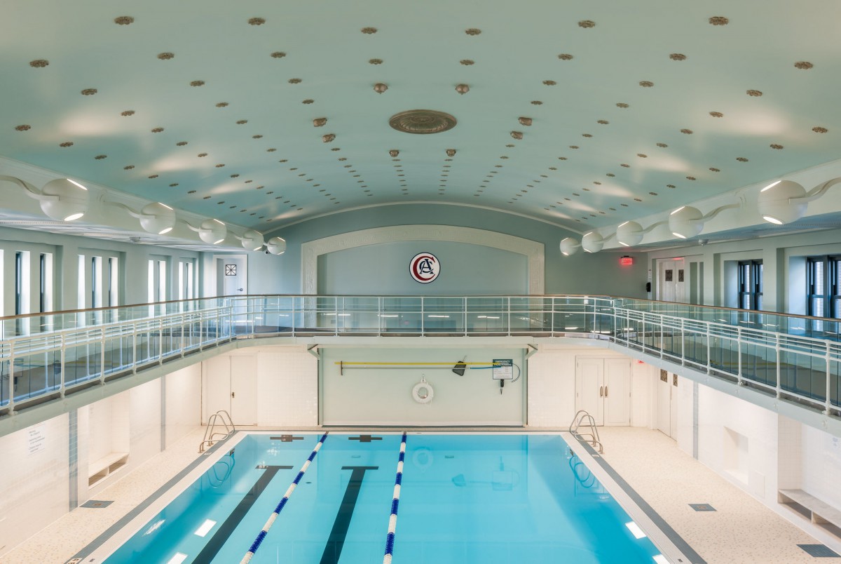 An empty indoor swimming pool with clearly marked lanes and bright overhead lighting.