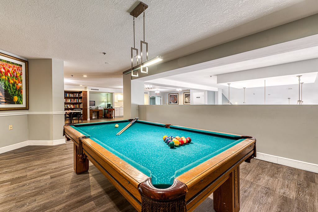A well-lit game room featuring a pool table with billiard balls arranged for play.
