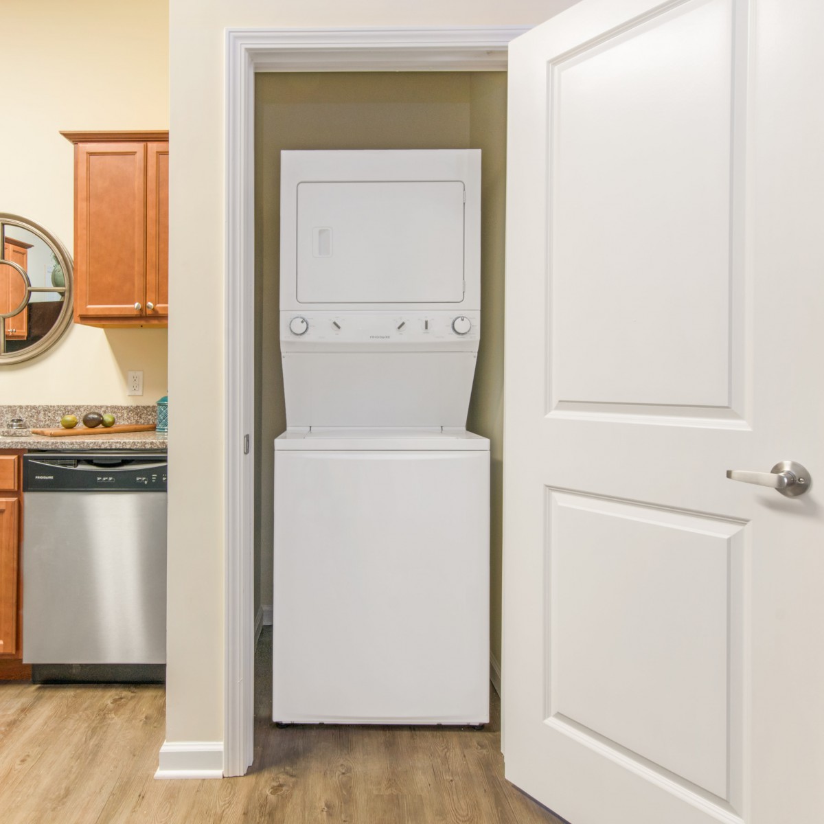 A compact laundry area with a stacked washer and dryer unit in a closet near a kitchen.