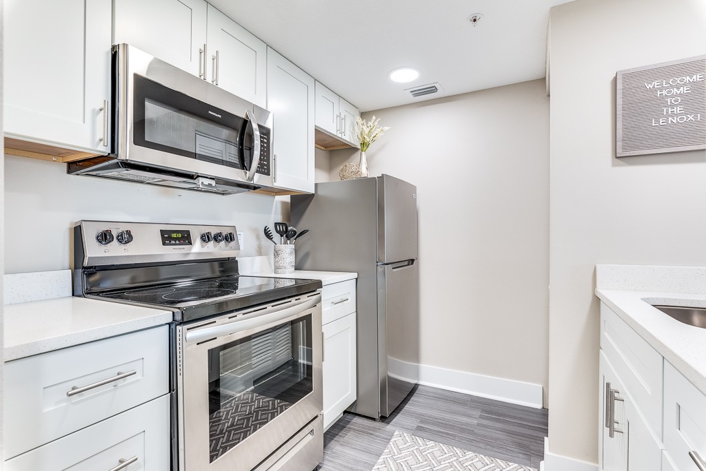 A compact modern kitchen featuring stainless steel appliances including a refrigerator, oven, and microwave.
