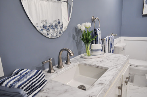 A modern bathroom setup featuring a marble sink, elegant mirror, and decorative flowers.