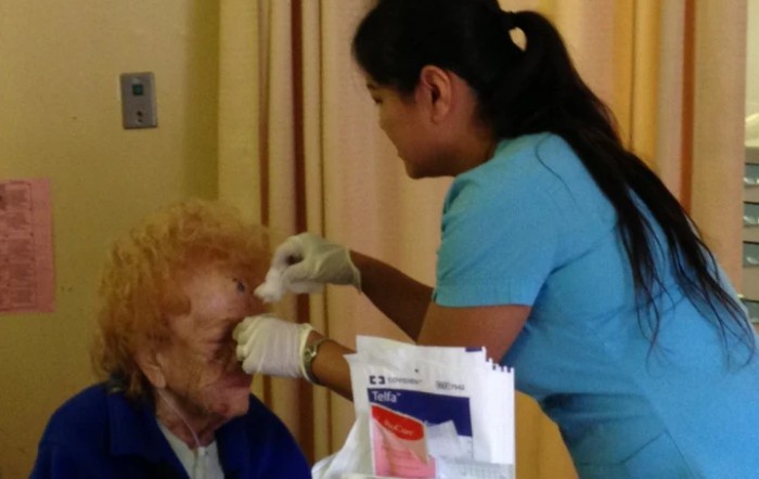 A healthcare professional attends to an elderly patient in a medical setting.
