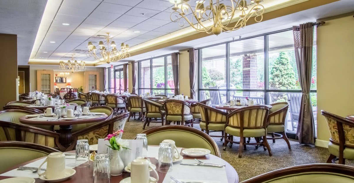A spacious and elegantly decorated dining area with multiple tables and chairs, set for service.