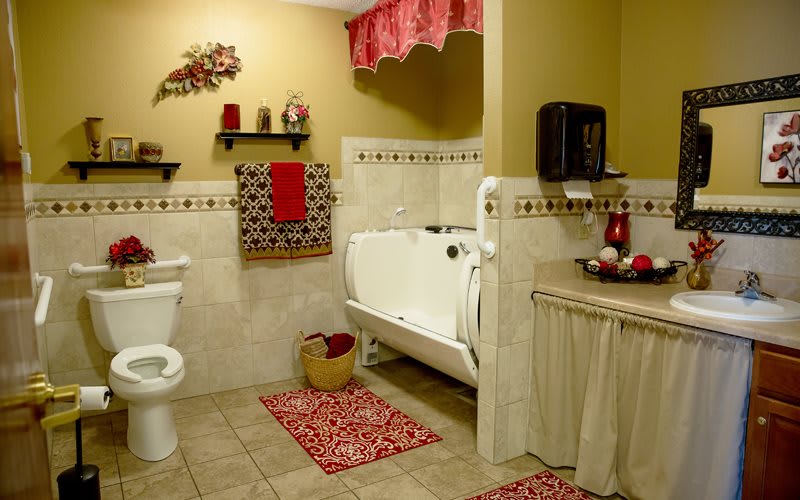 A traditional bathroom with red decorative accents and a tiled floor.