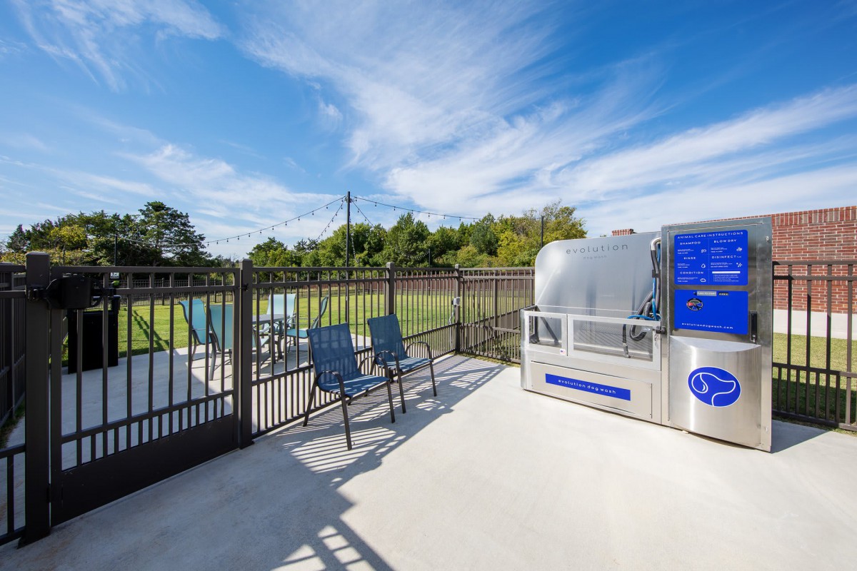 Outdoor vending machine area with chairs and fence under a clear sky.