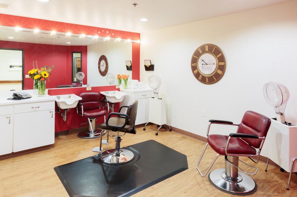 A modern hair salon interior with red and white decor, styling chairs, and mirrors.