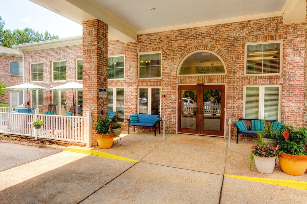 The entrance to a brick building with outdoor seating and potted plants.