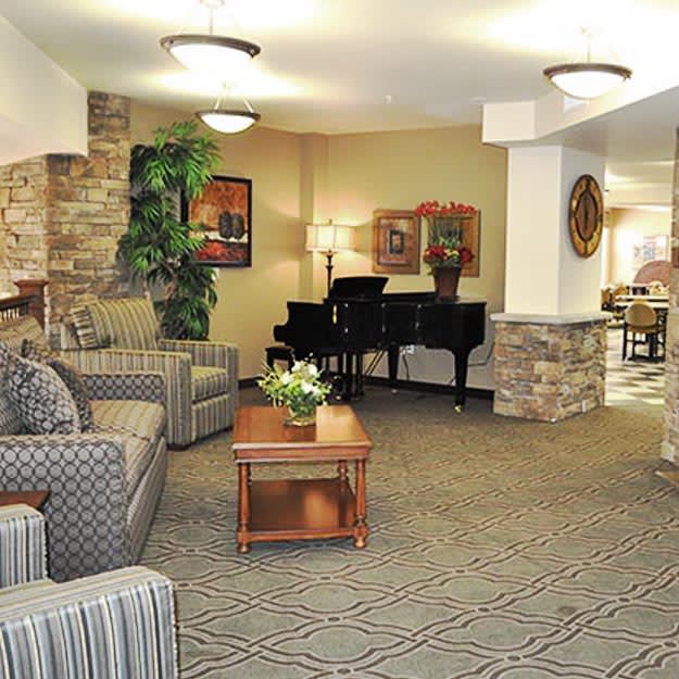 A warmly decorated lobby featuring comfortable seating, a grand piano, and tasteful decor.