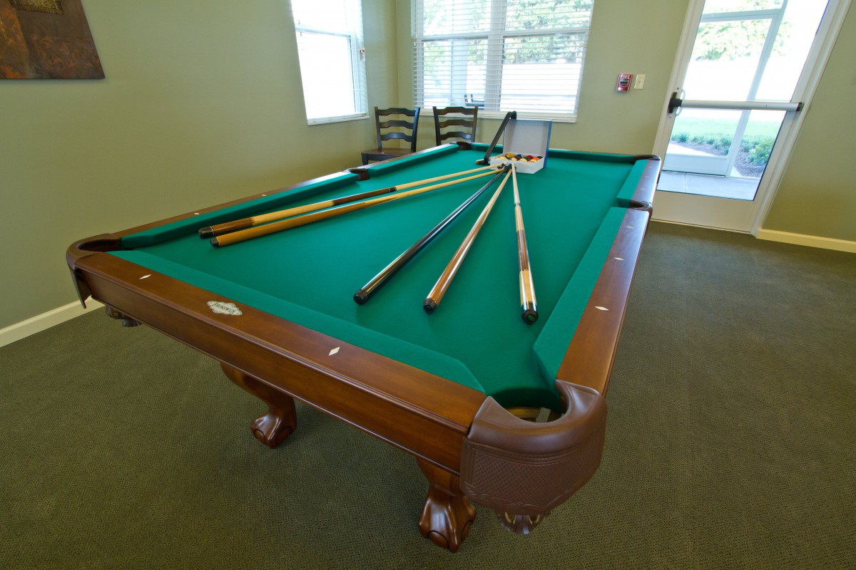 A pool table set up with cue sticks, ready for a game of billiards in a well-lit room.