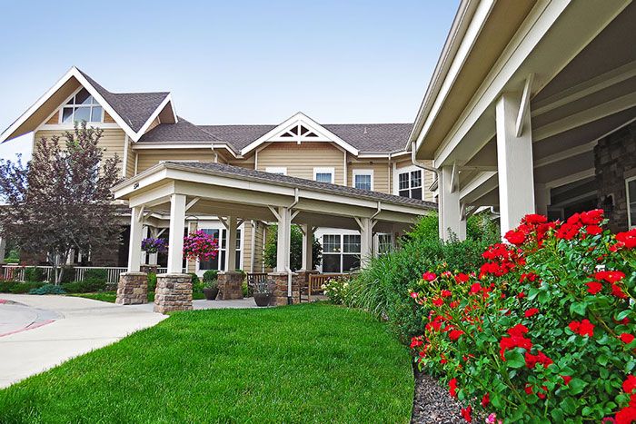 A beautifully landscaped residential building with lush green lawns and vibrant flower beds.