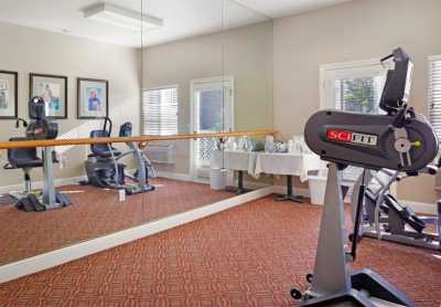 A small indoor gym with fitness equipment, including a treadmill and an exercise bike, reflected in a large mirror.