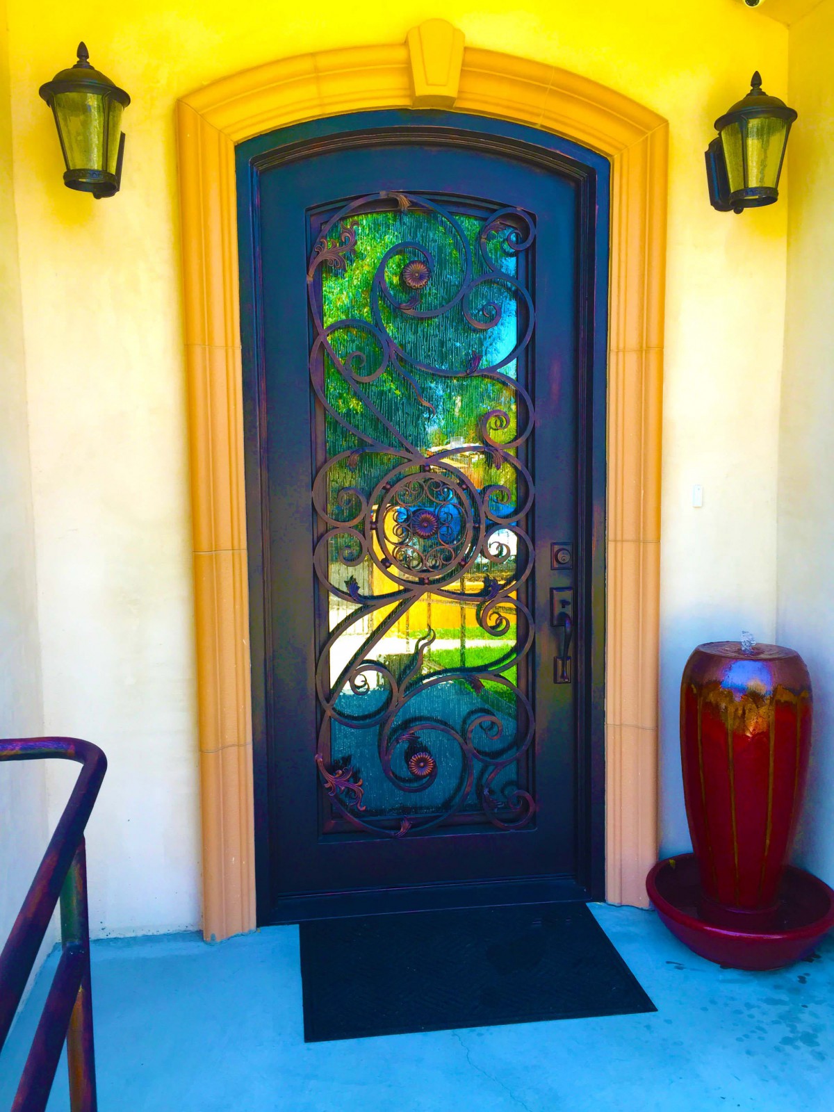 A decorative entrance with an ornate door featuring stained glass and intricate ironwork.