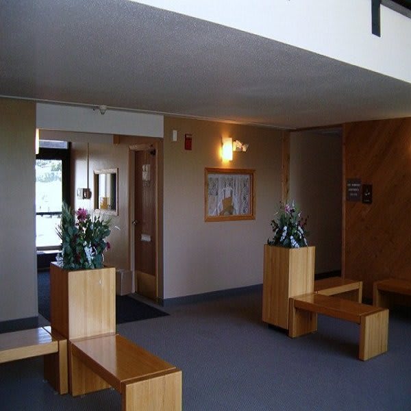 A lobby area with wooden benches, potted plants, and a hallway.