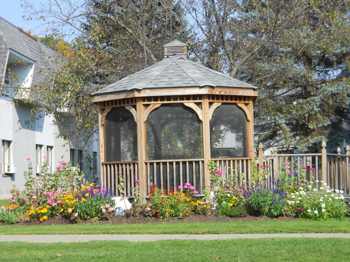 A wooden gazebo surrounded by a colorful garden.