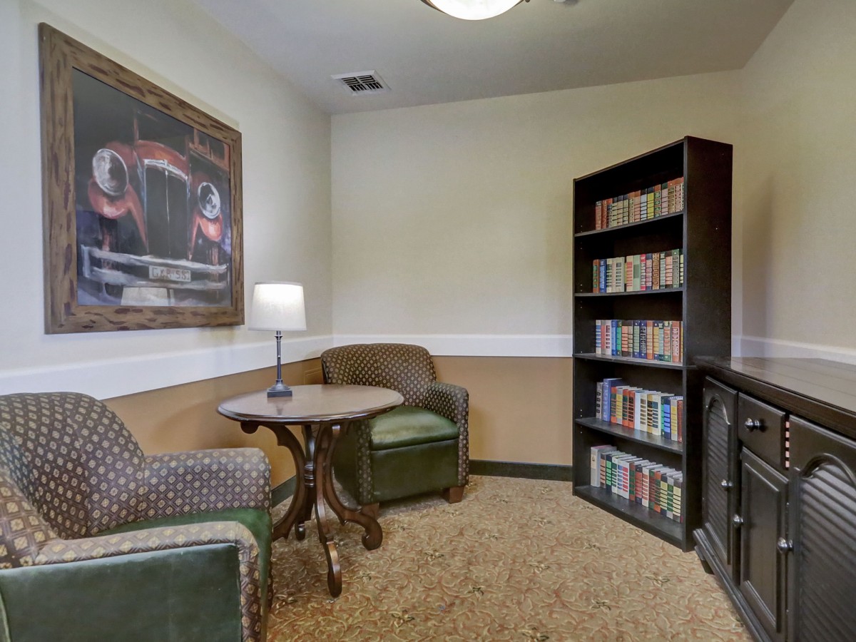Cozy reading nook with armchairs, a lamp, and a bookshelf filled with books.