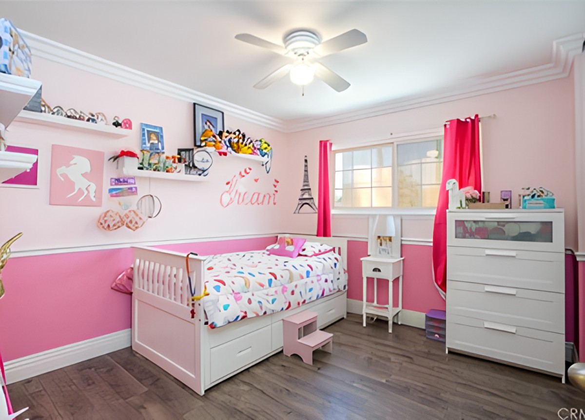 A cozy nursery with pink decor featuring a crib, shelves with toys, and vibrant curtains.