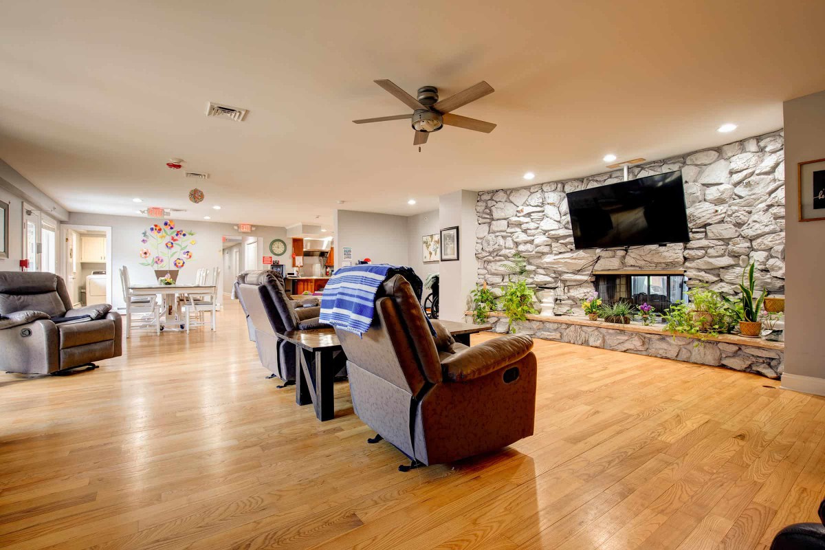 A cozy living room featuring comfortable recliners, a stone fireplace with a mounted television, and wooden flooring.