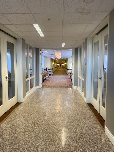 A view down a well-lit corridor with glass doors on either side.