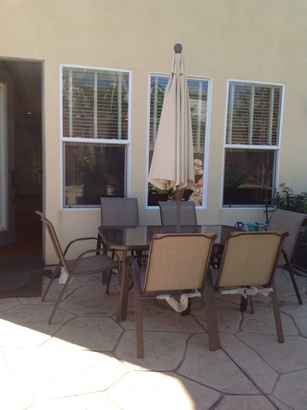 Outdoor patio area with a table, chairs, and an umbrella in front of a house.