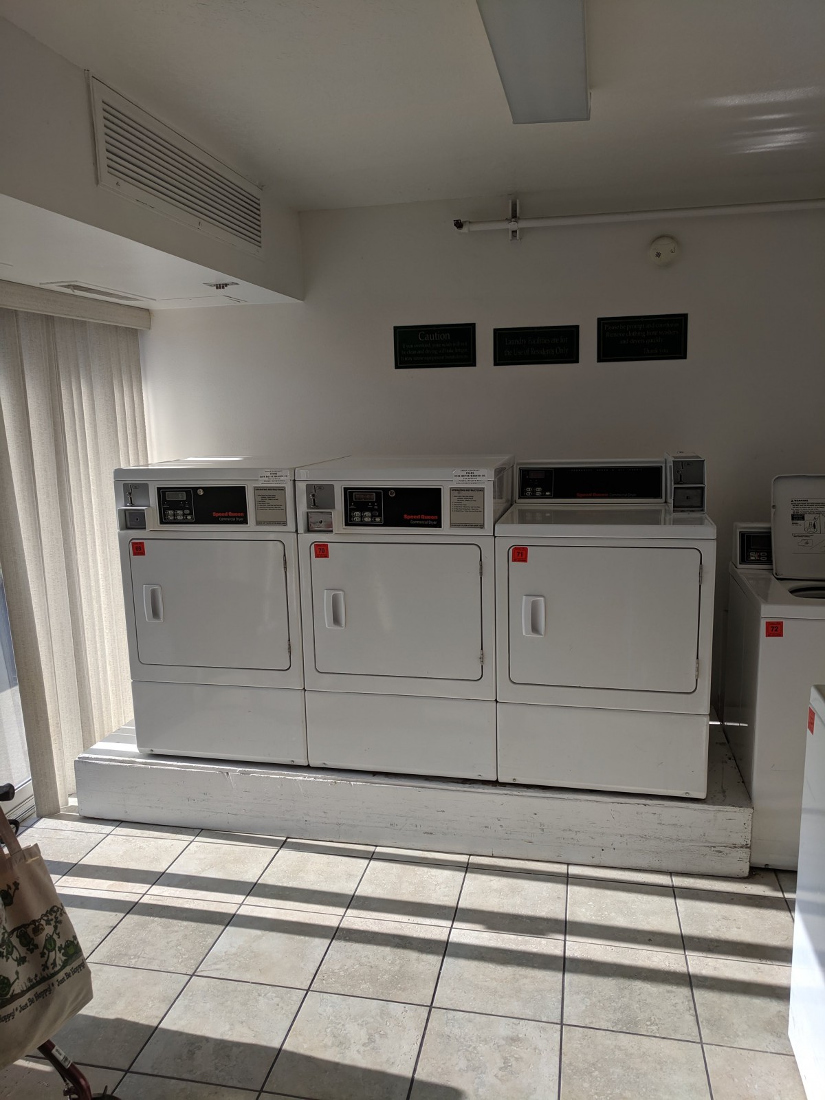 A laundry room with multiple dryers aligned against the wall.