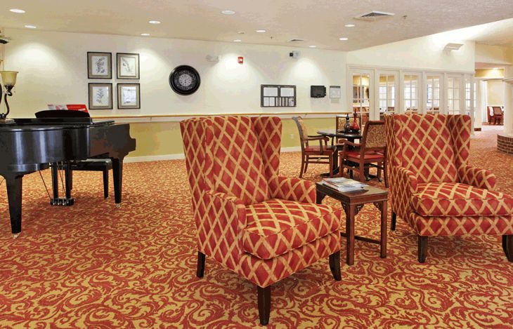 A cozy lounge area with patterned chairs, tables, and a grand piano.