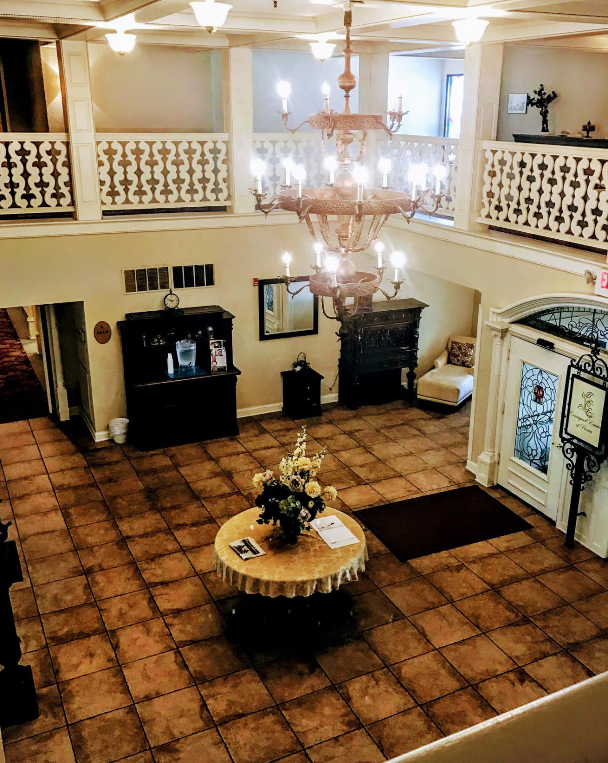 A grand hotel lobby featuring a large chandelier and an elegant table centerpiece.