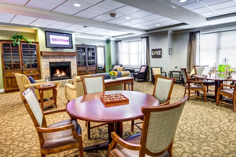 A cozy living room with a fireplace, seating area, and table set for games.
