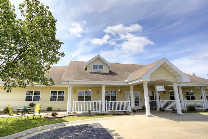 A charming yellow house with a welcoming front porch under a partly cloudy sky.