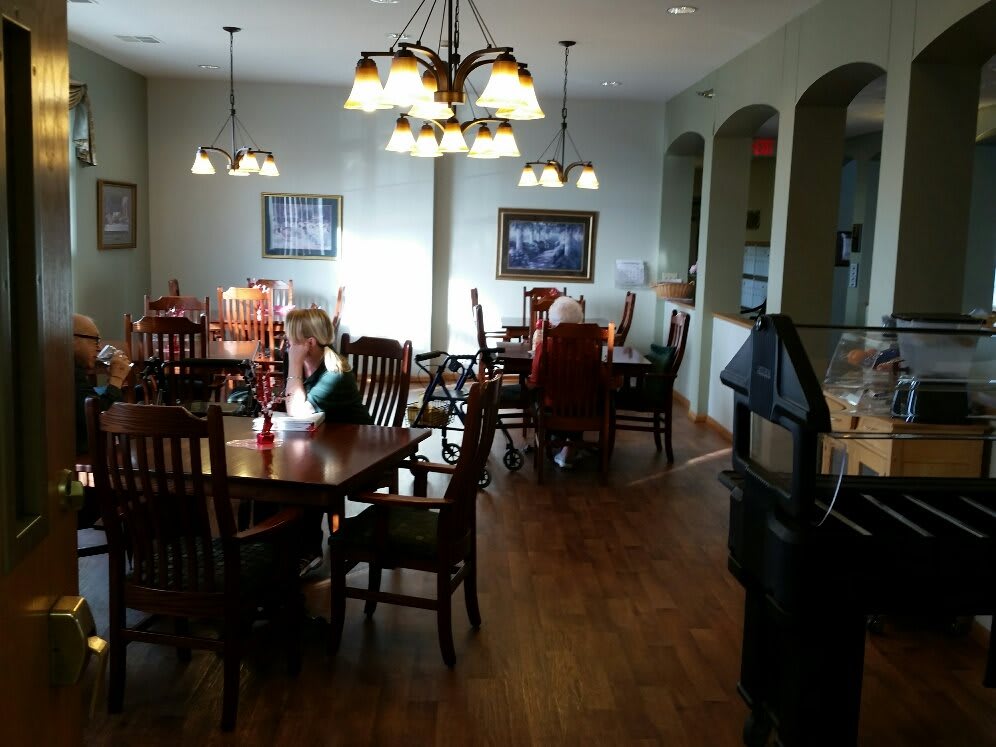 A cozy dining area with wooden tables and chairs, illuminated by chandeliers.