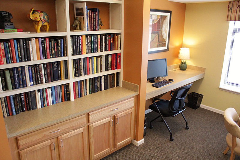 A cozy home office with a well-stocked bookshelf and a tidy computer workstation.