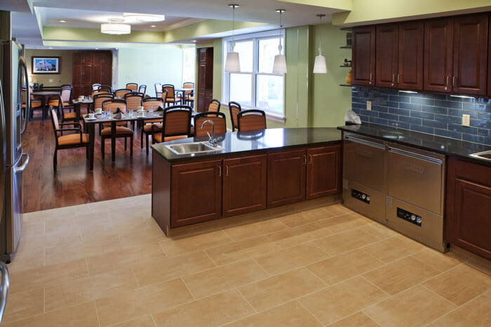 A spacious kitchen area with wooden cabinets and a dining area in the background.