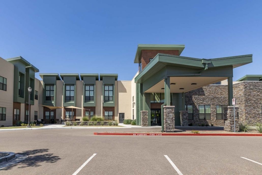 A modern hotel building with a spacious parking area and a prominent entrance.