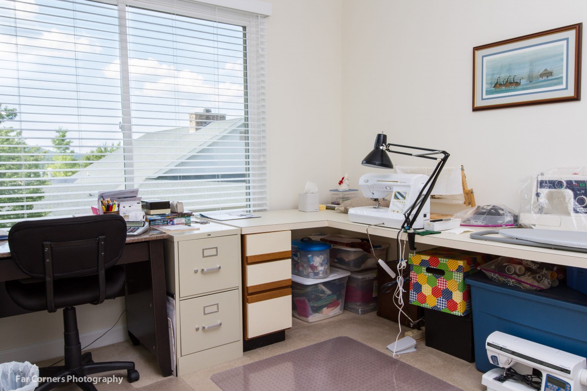 A well-organized home office with a desk, lamp, and filing cabinets near a window.