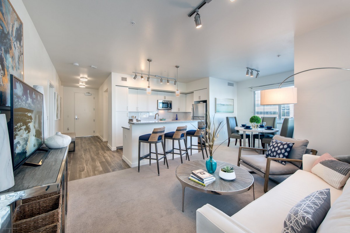 A modern open-concept apartment featuring a living room, kitchen, and dining area.