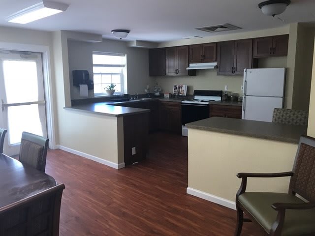 A modern kitchen with wood flooring and dark cabinets.