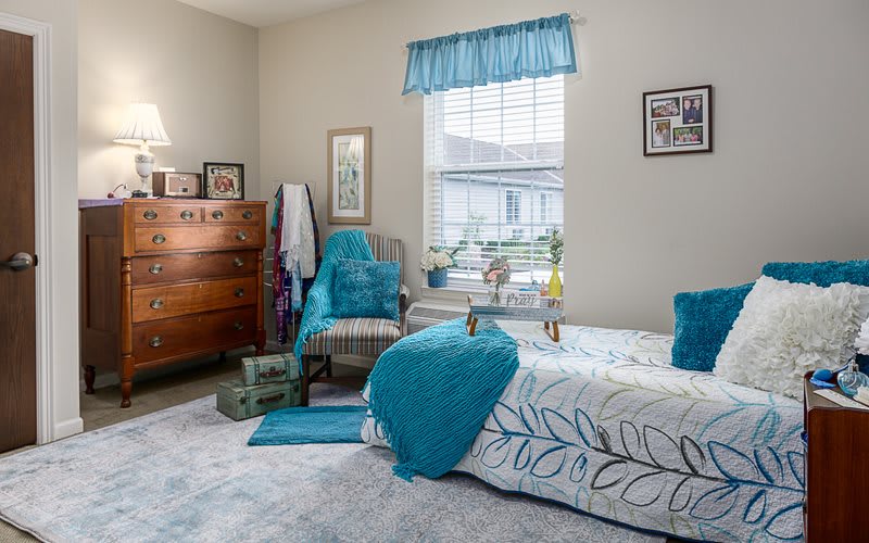 A cozy bedroom with turquoise accents and natural light pouring in through the window.