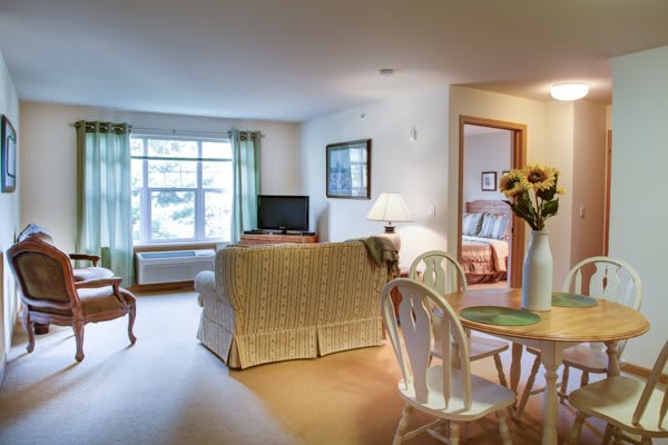 A cozy living room with a dining area, featuring a sofa, television, and wooden furniture.