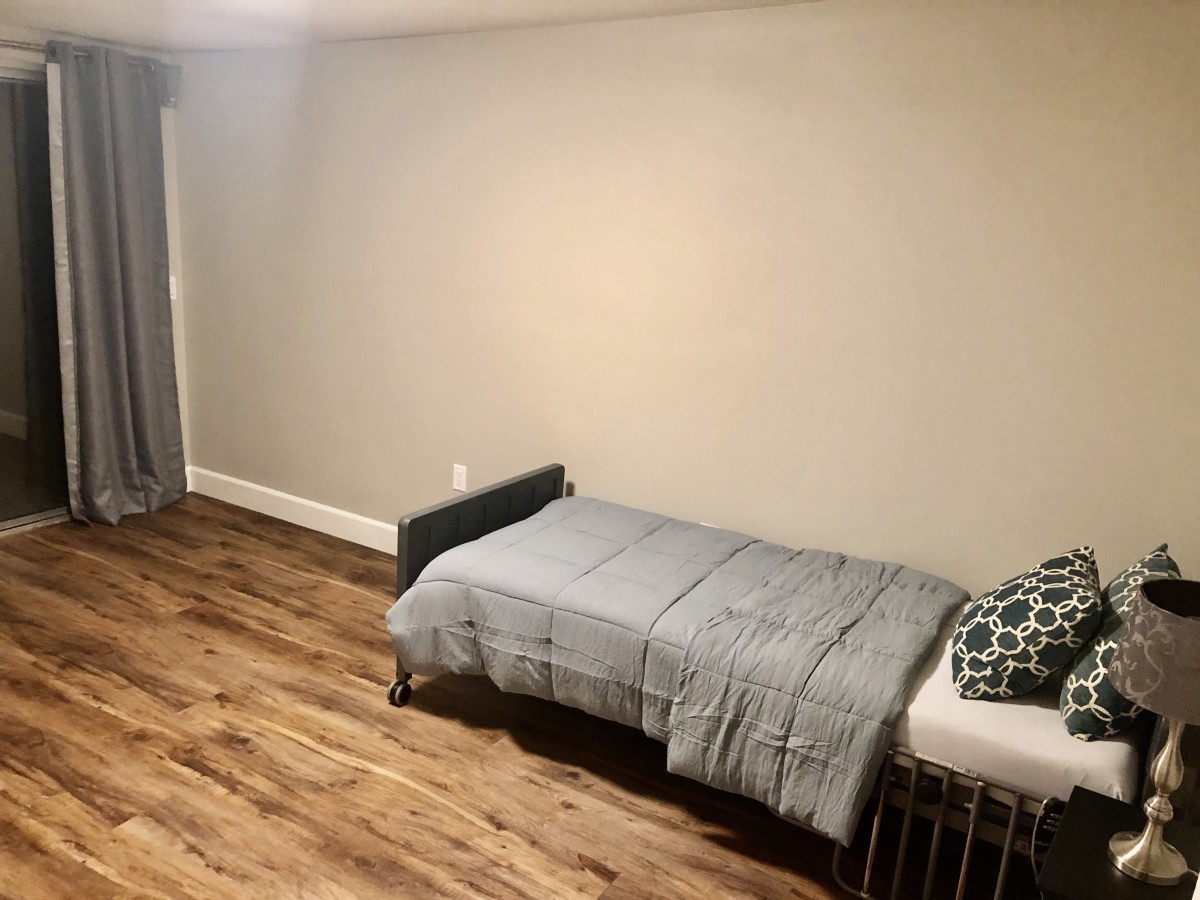 A minimalist bedroom with a single bed and wooden flooring.
