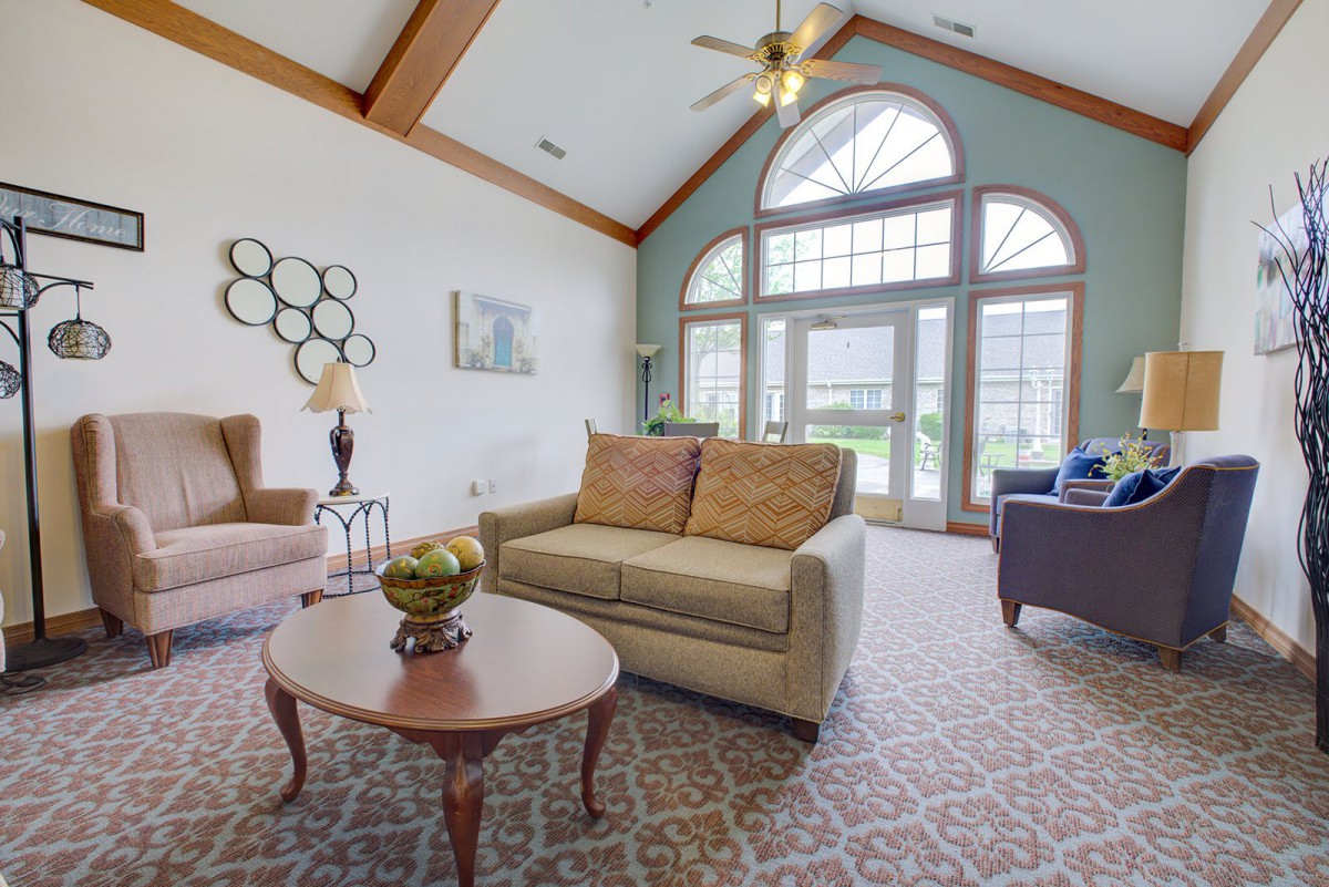 A cozy living room with a vaulted ceiling, featuring a sofa and coffee table in front of large windows.