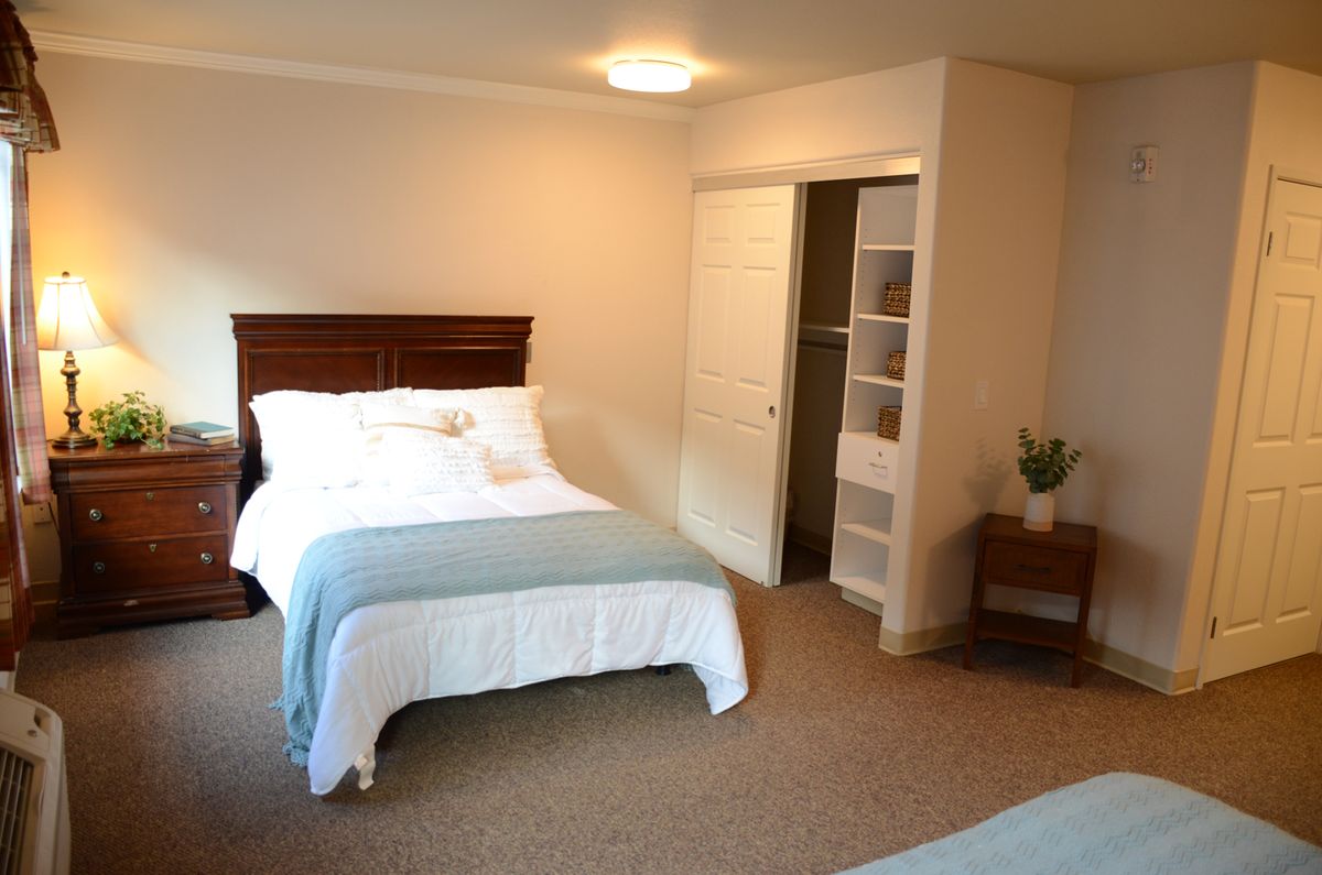 A cozy bedroom with a neatly made bed and an adjacent open closet.