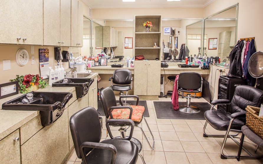 An empty hair salon with chairs and mirrors lined up, ready for customers.