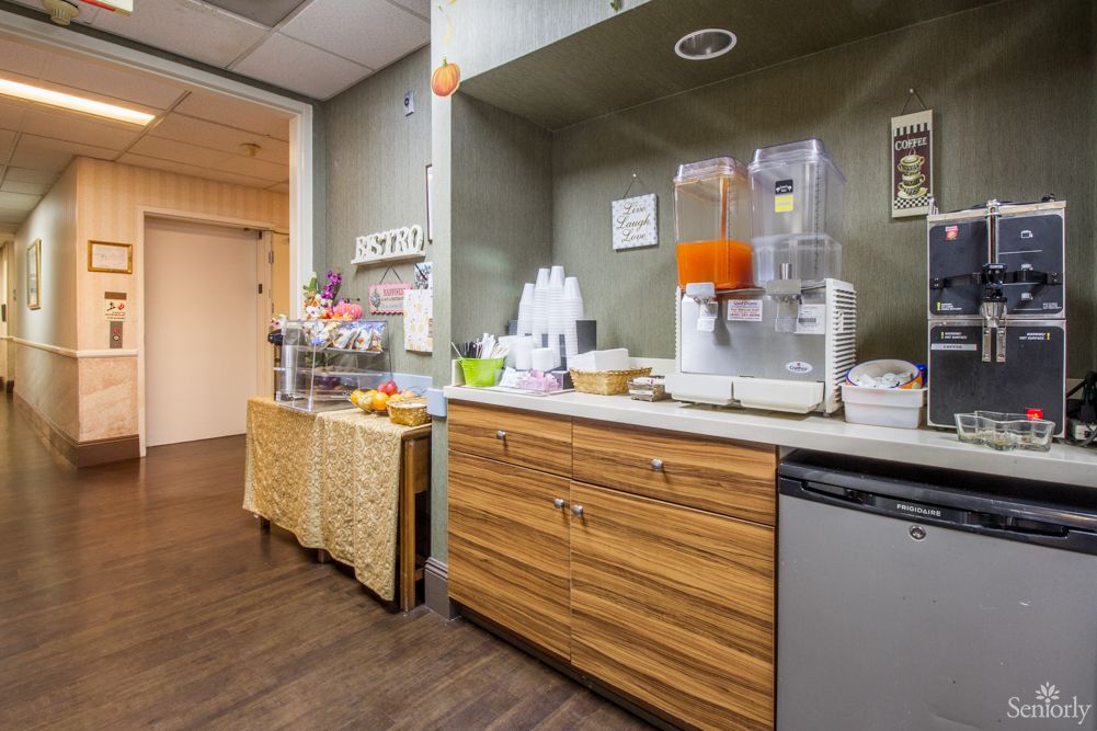 Office break room with a beverage station and wooden cabinets.