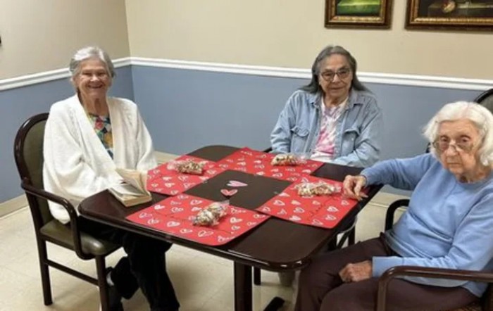 Three seniors sitting at a table enjoying a leisure activity.
