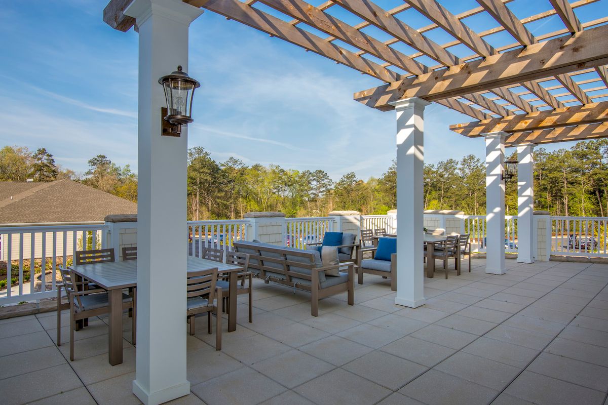 A spacious outdoor patio with a pergola and comfortable seating, surrounded by nature.